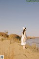 A woman standing on top of a sand dune next to a river.