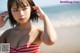 A woman in a red and white striped bikini on the beach.