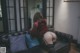 A woman in a red shirt and black stockings sitting on a couch.