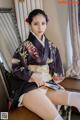A woman in a kimono sitting on a chair.