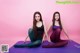 Two young women sitting on a purple yoga mat.