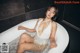 A woman in a white bathing suit sitting in a bathtub.